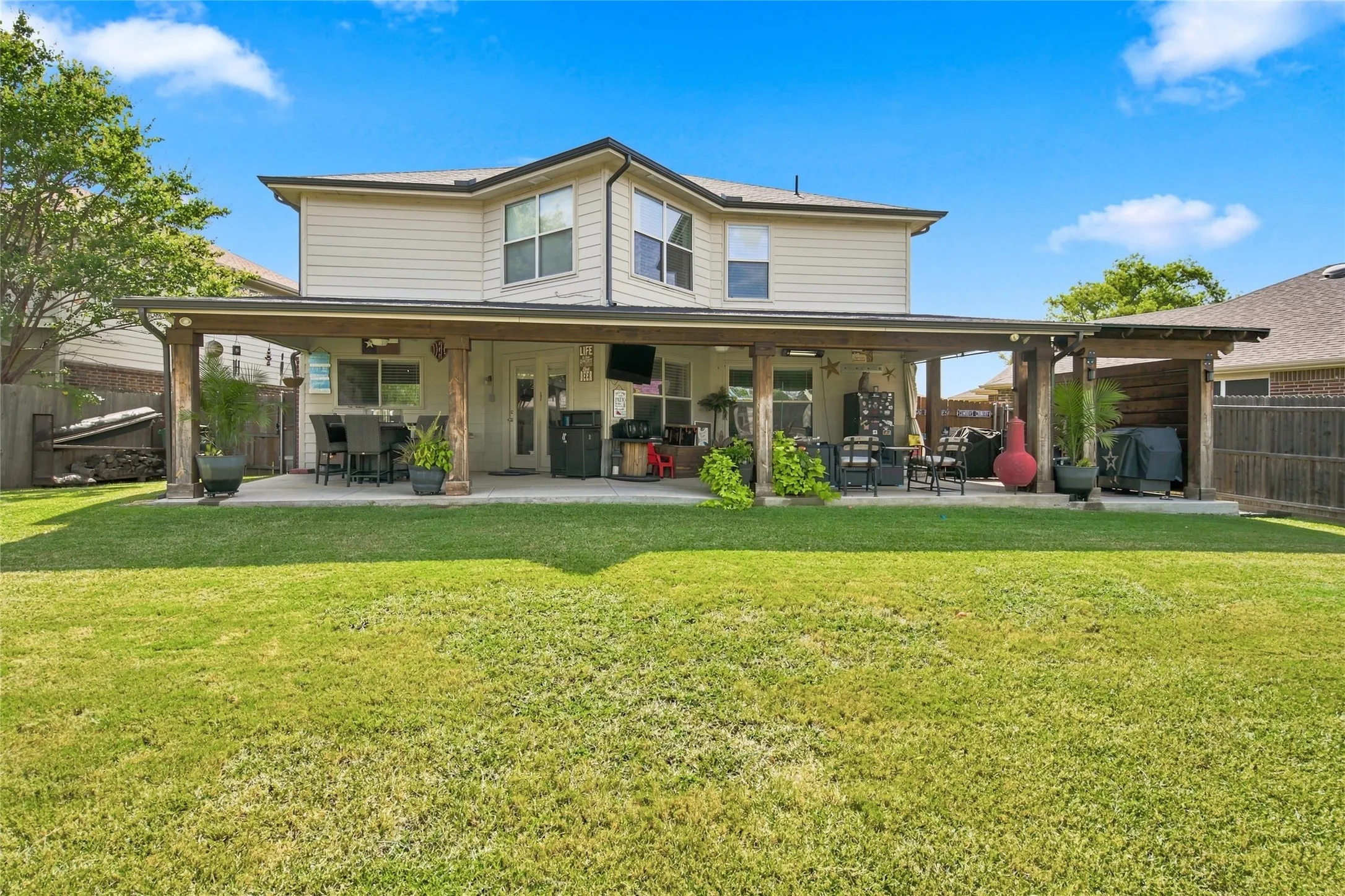 Expansive backyard featuring a manicured lawn, a full-length covered patio, and a separate covered outdoor structure