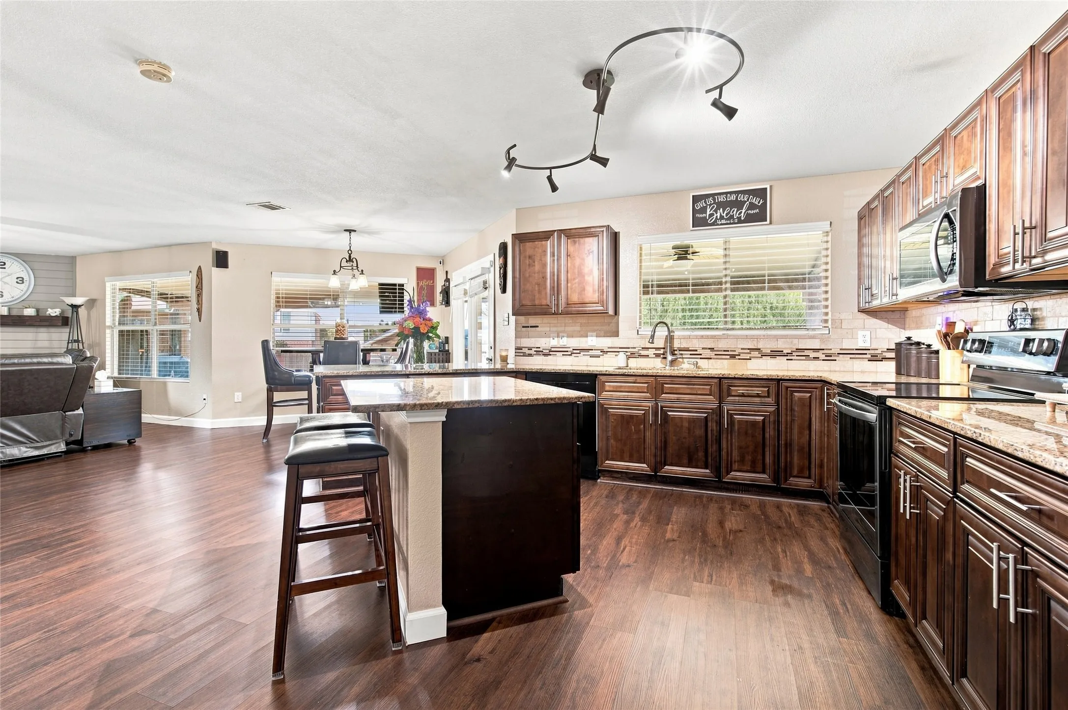 Expansive kitchen featuring dark wood-finish cabinetry, light-toned countertops, a full suite of stainless-steel appliances, and wood-finish flooring