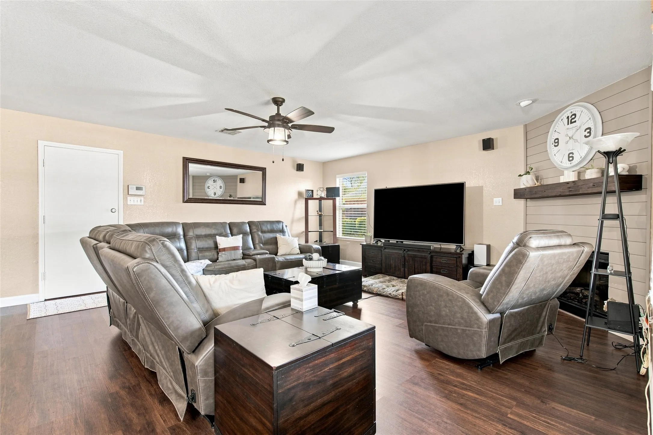 Wood-finish flooring throughout, ceiling fan, fireplace with mantel, and built-in shelving