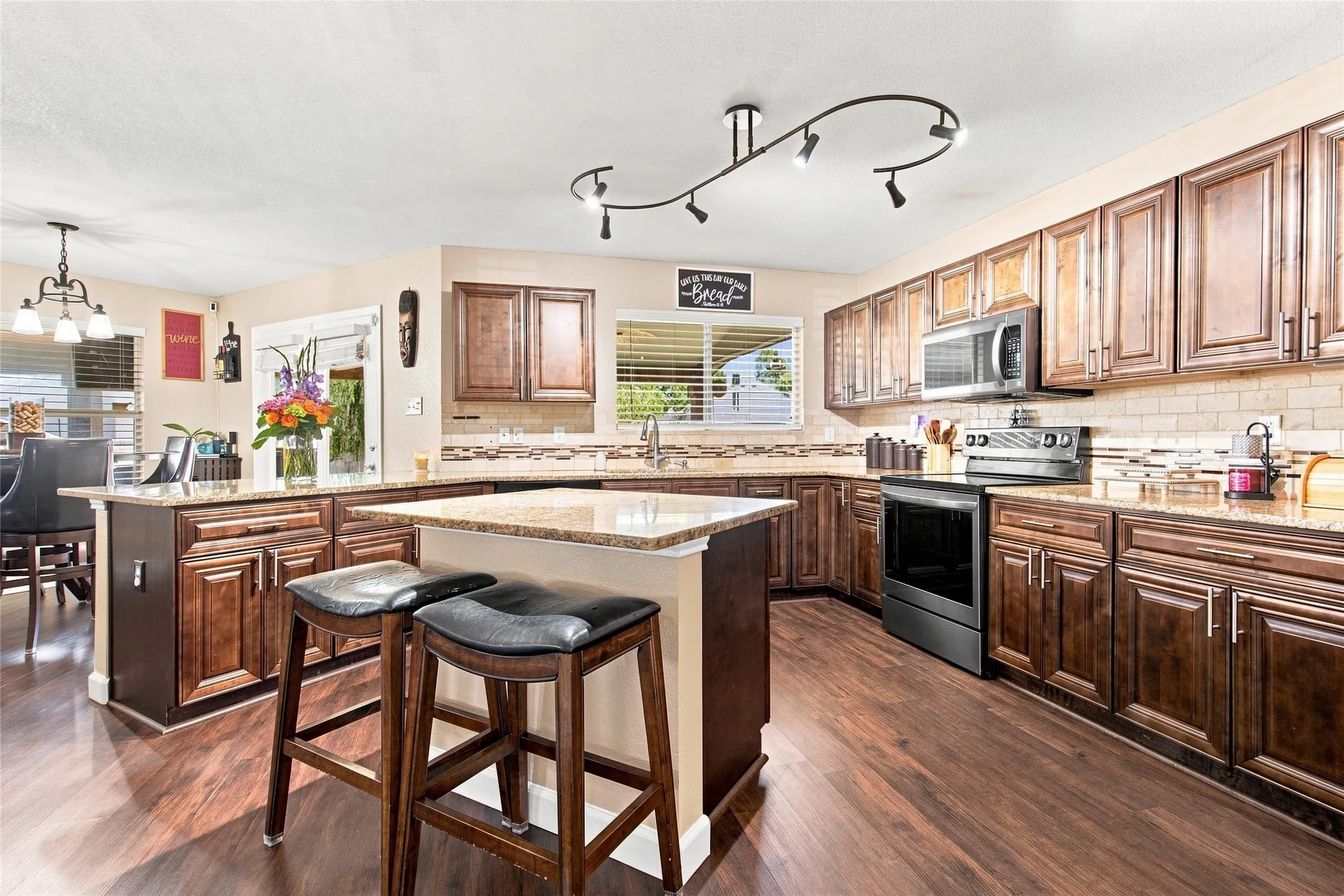 Kitchen featuring wood-finish flooring, wood cabinetry, stone countertops, and a tile backsplash