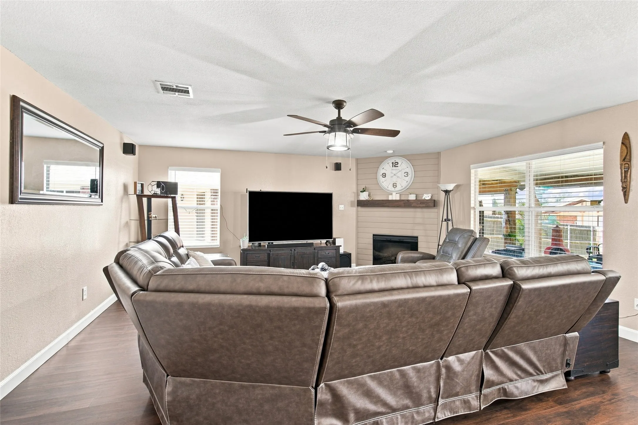 Wood-finish flooring, ceiling fan with integrated lighting, built-in fireplace, and expansive rear windows