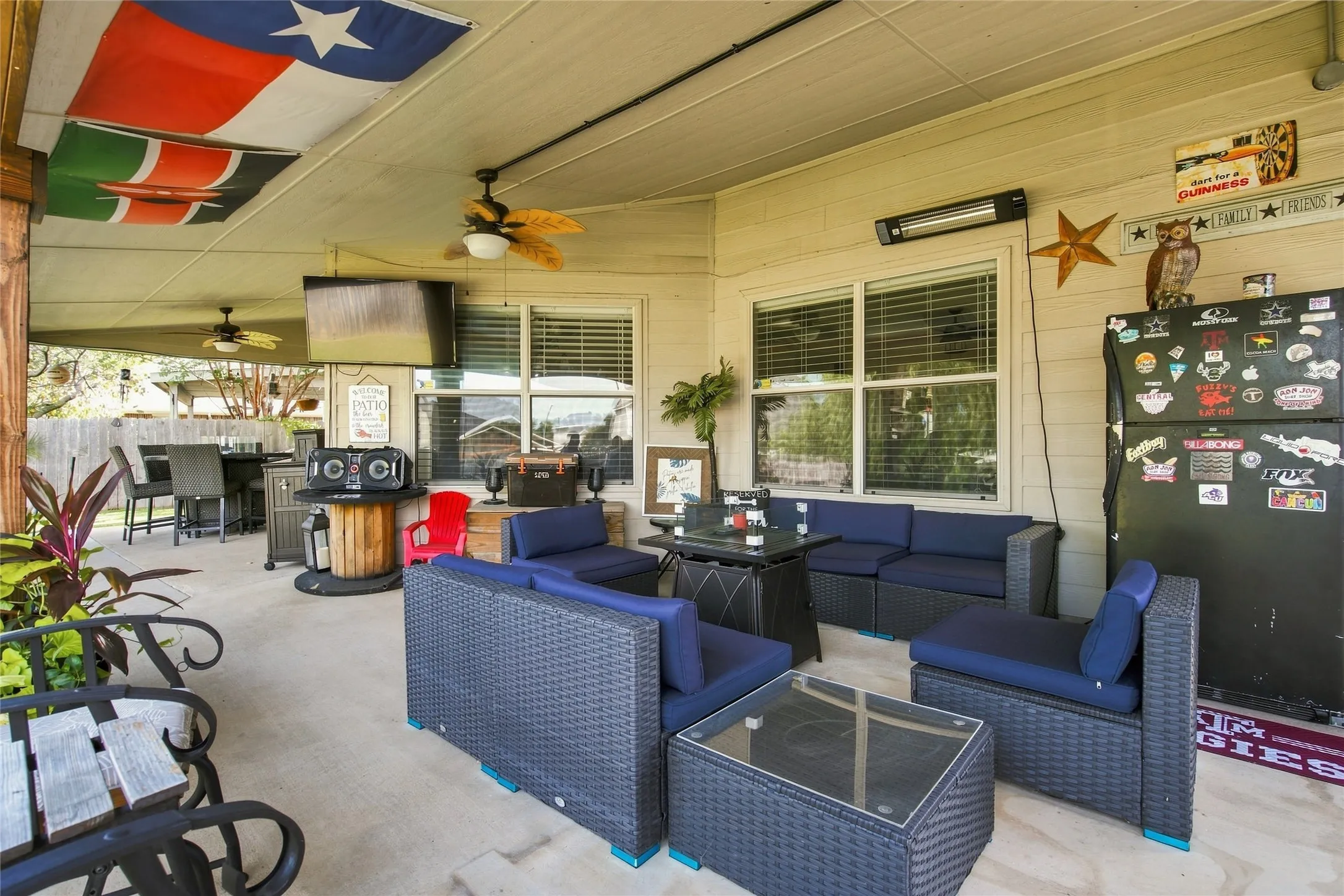 Expansive covered patio with concrete flooring, multiple ceiling fans, and a built-in outdoor heater