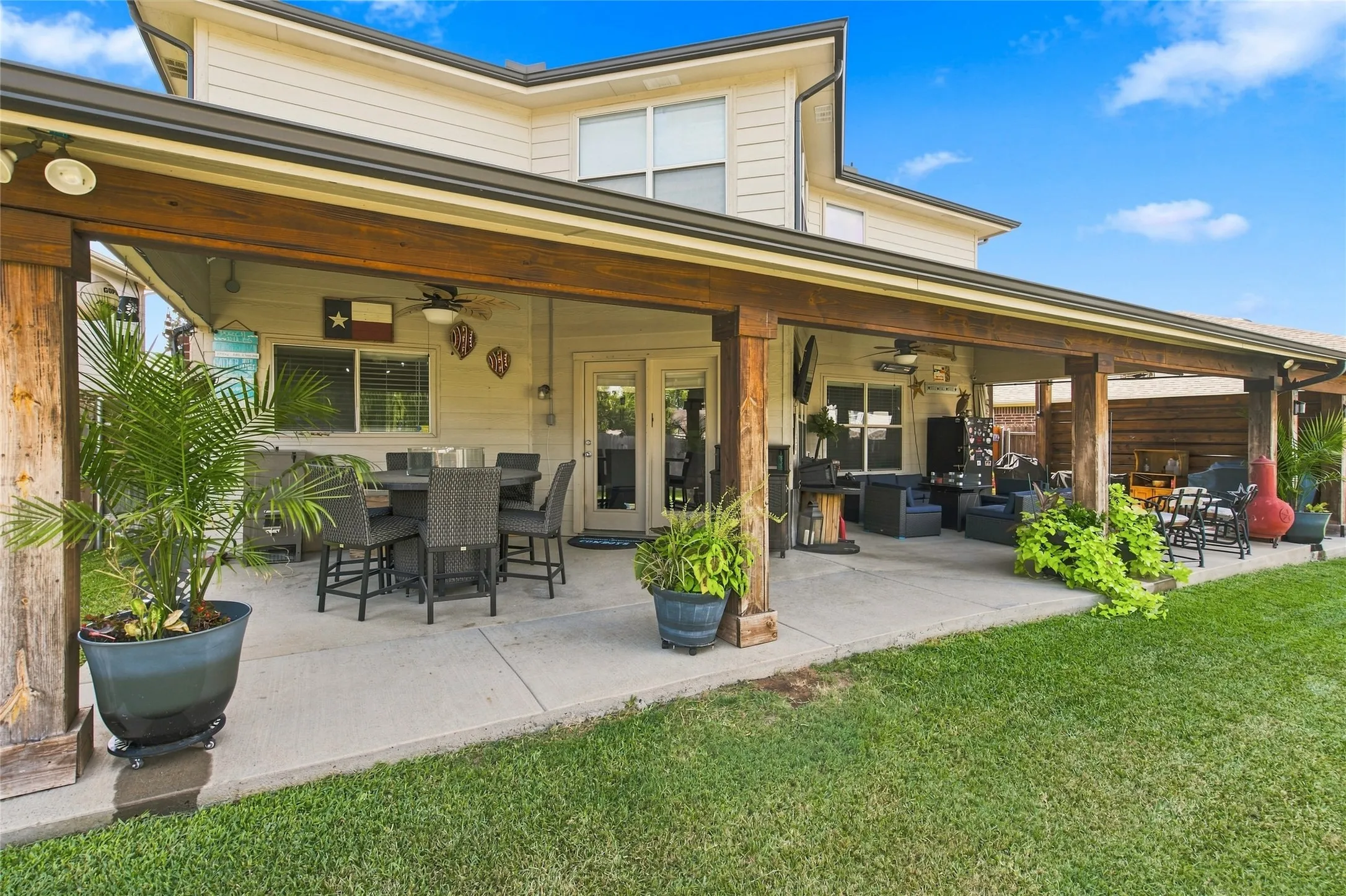 Expansive covered patio featuring a concrete surface, exposed wood beams, ceiling fans, and recessed lighting
