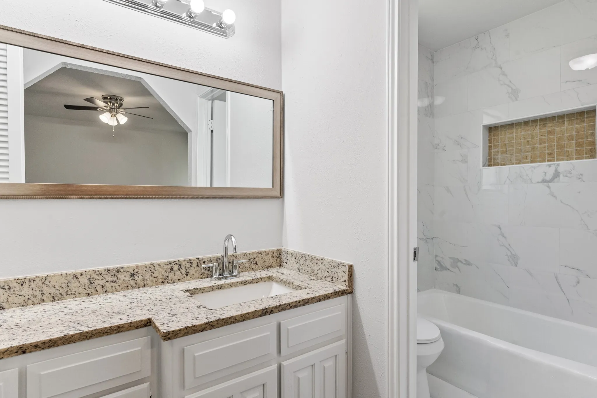 Vanity with granite countertop, integrated sink, and chrome faucet