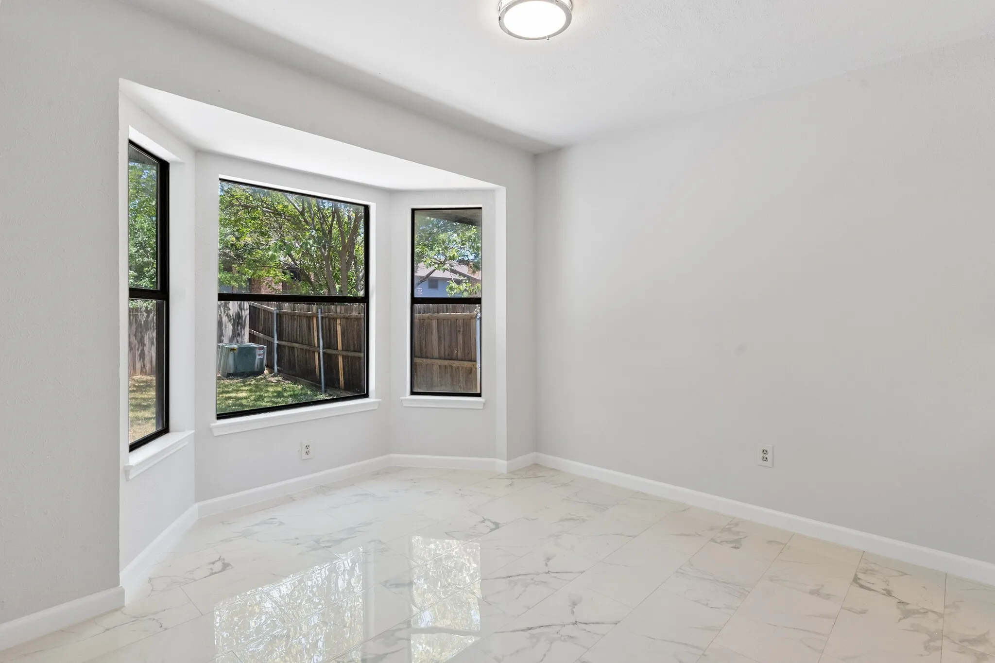 Bay window with black trim, white walls, and a flush mount ceiling light