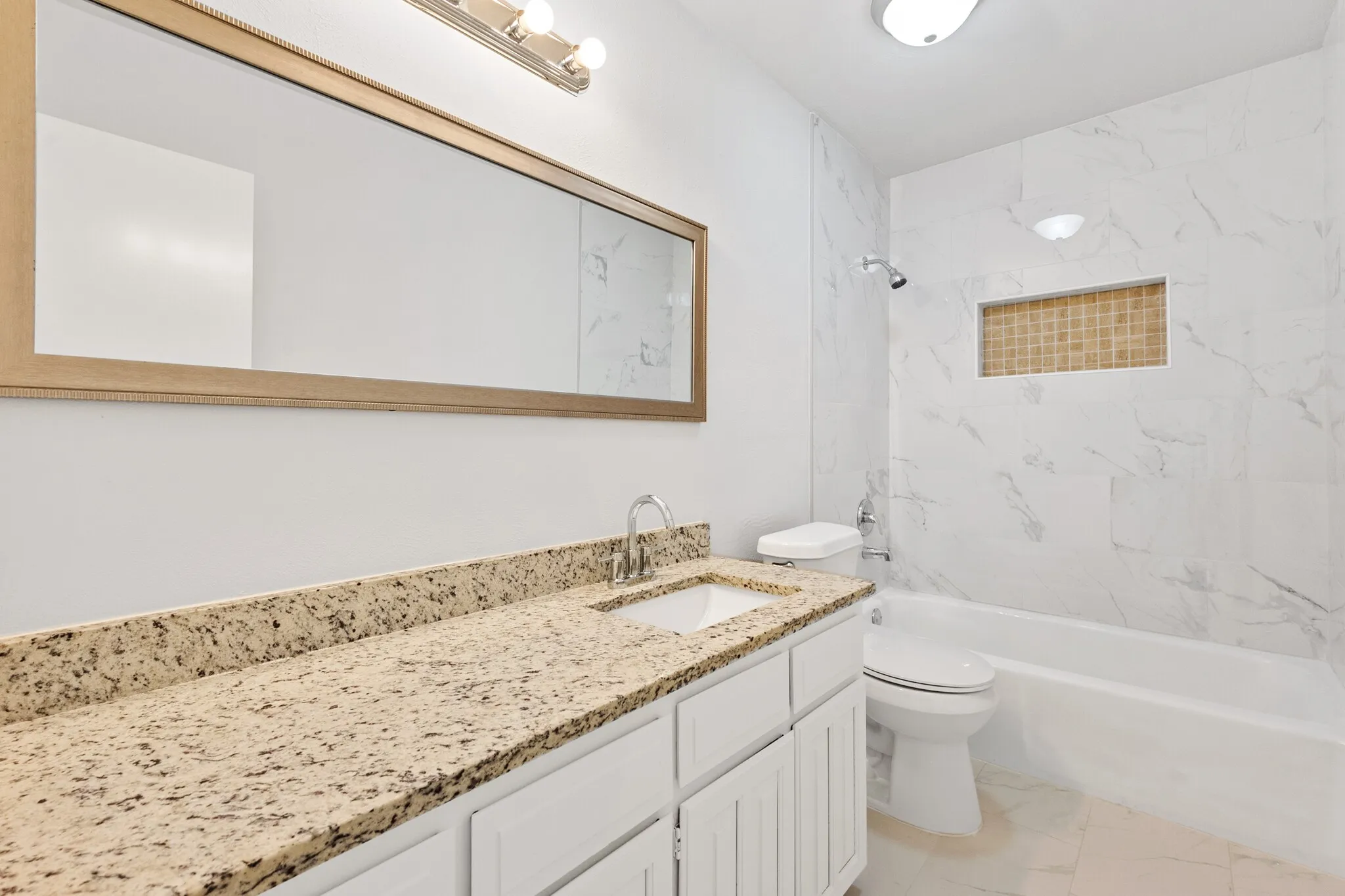 White vanity with speckled countertop, undermount sink, and chrome faucet