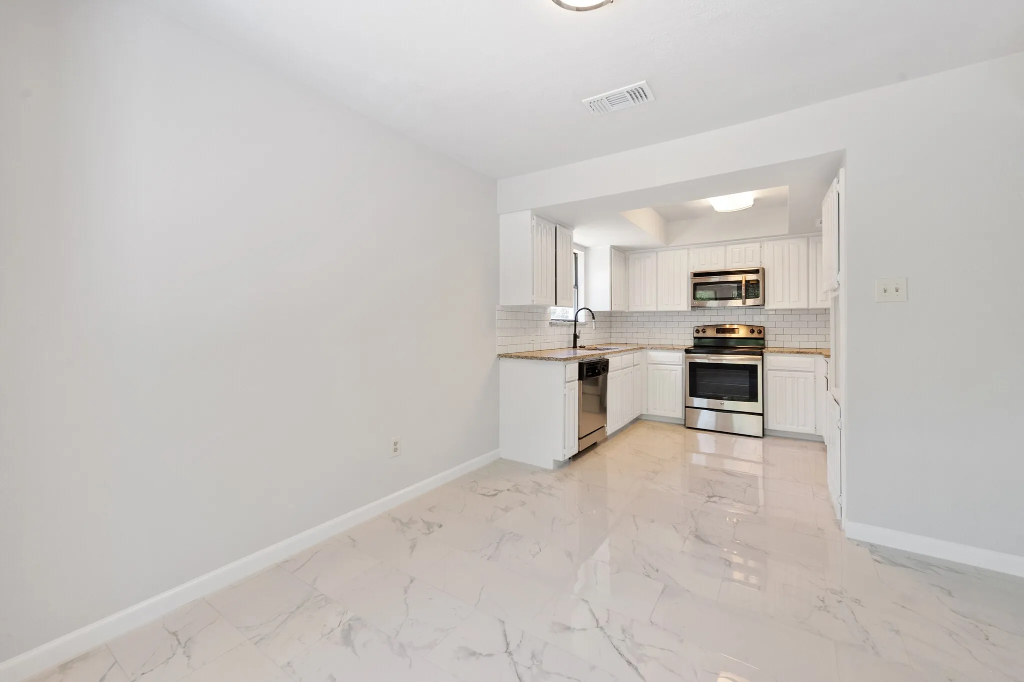 Kitchen featuring stainless steel appliances, white cabinetry, solid surface countertops, and white subway tile backsplash