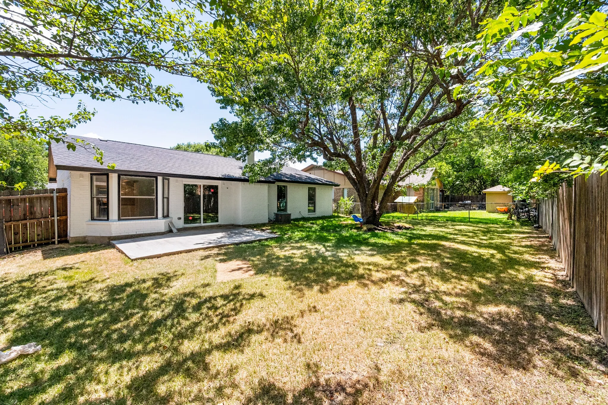 White exterior with a dark roof and a large concrete patio