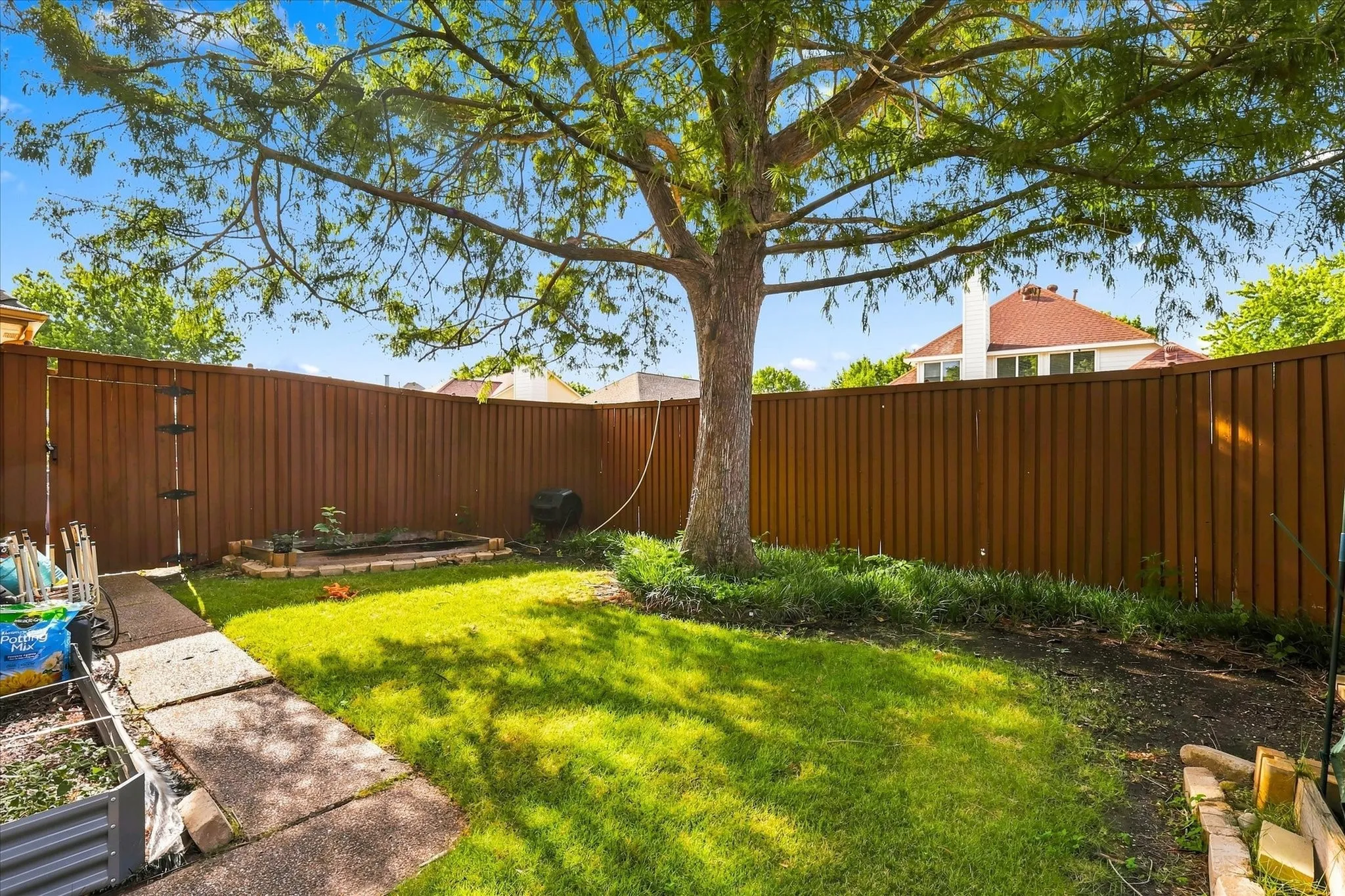 Beauitiful backyard with shaded tree and cedar board on board 8' fence