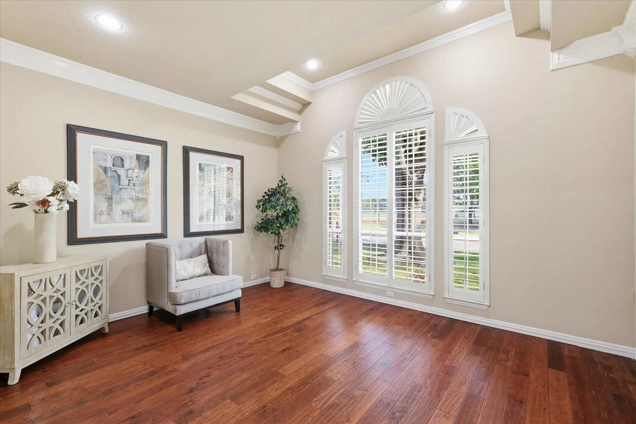 Living area facing front with high ceilings, plantation shutters and wood floors
