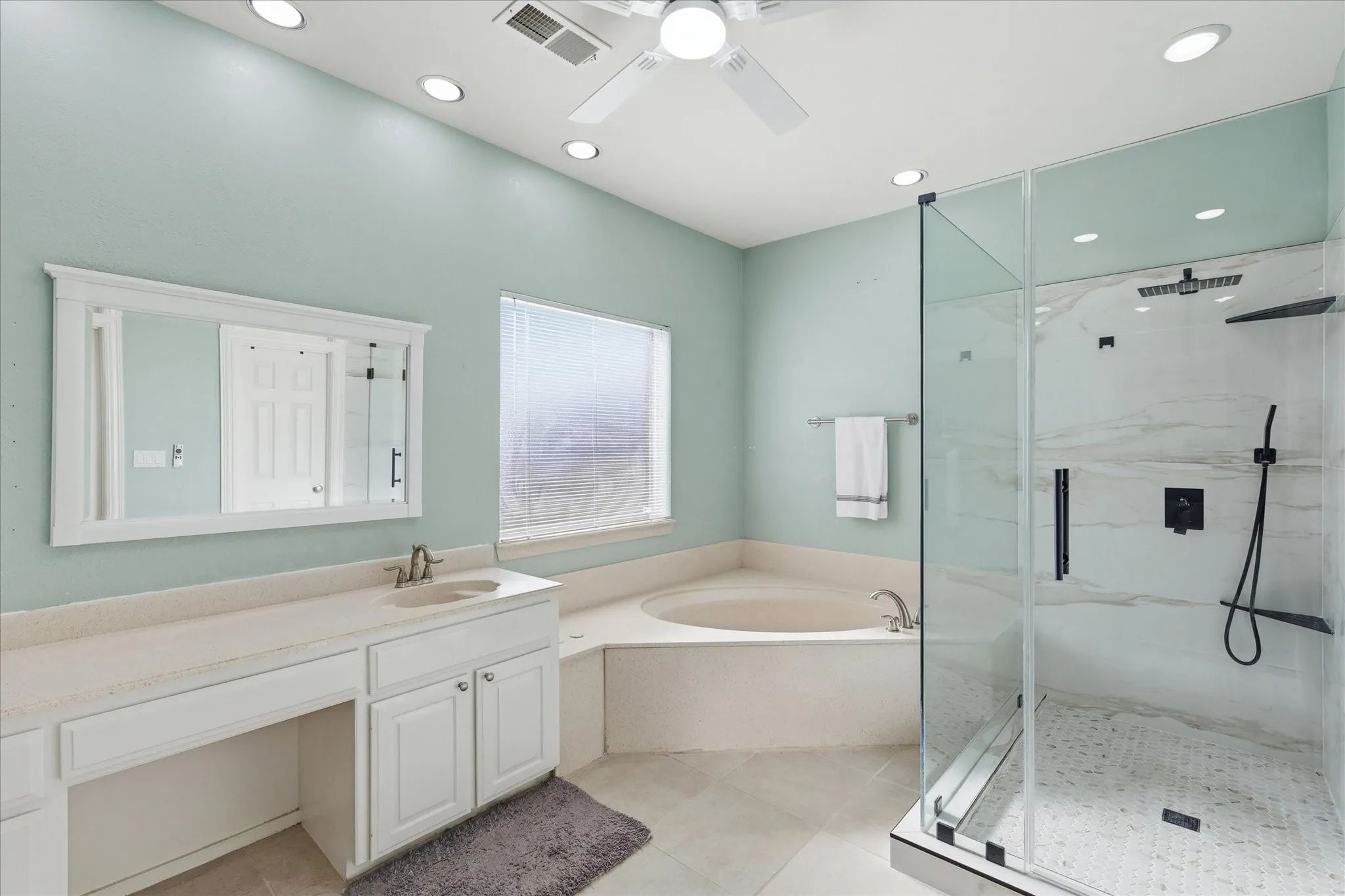 Updated shower with seamless glass enclosure, sitting area and tiled floor