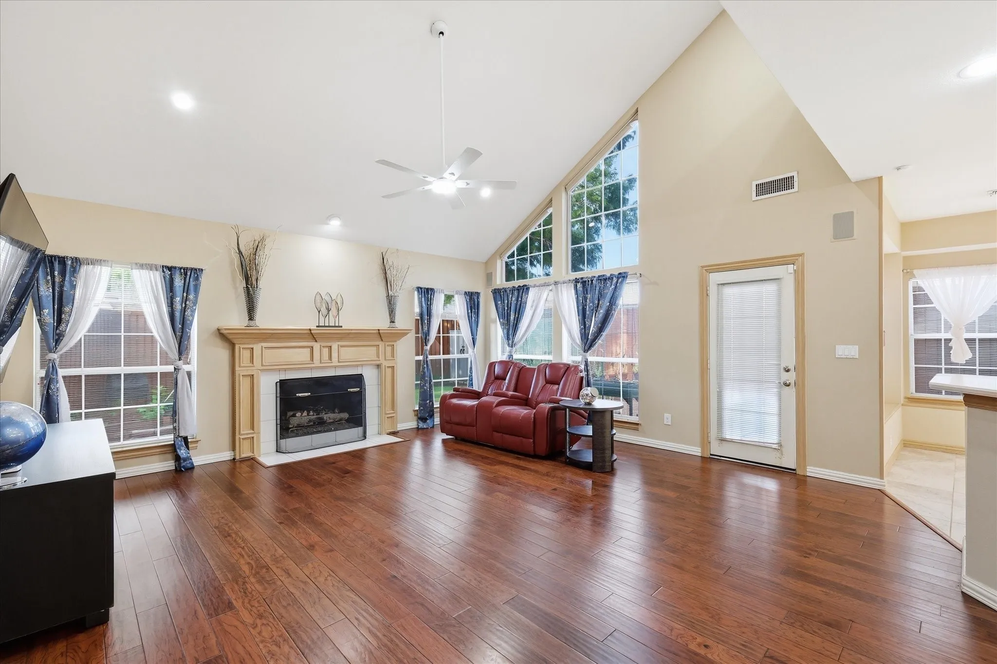 Downstairs oversized family room with wood floors, vaulted ceilings, lots of natural light, fireplace, ceiling fan and open to kitchen area.