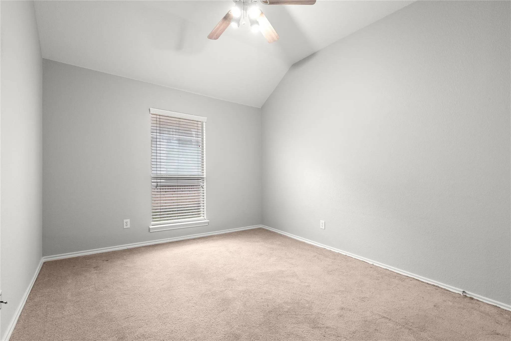 Vaulted ceilings with a ceiling fan, neutral wall paint, carpet flooring, and a single window with blinds