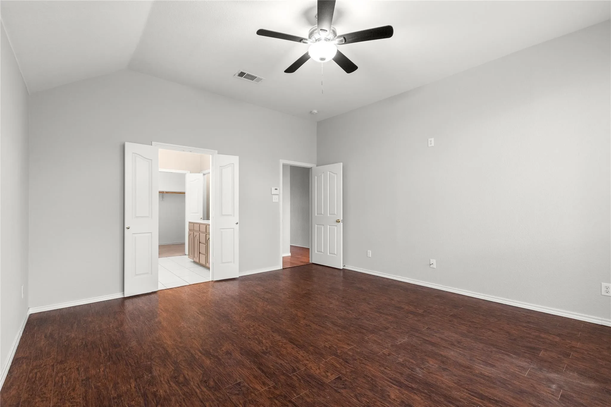 Vaulted ceilings with a ceiling fan, wood-finish flooring, and light-toned walls