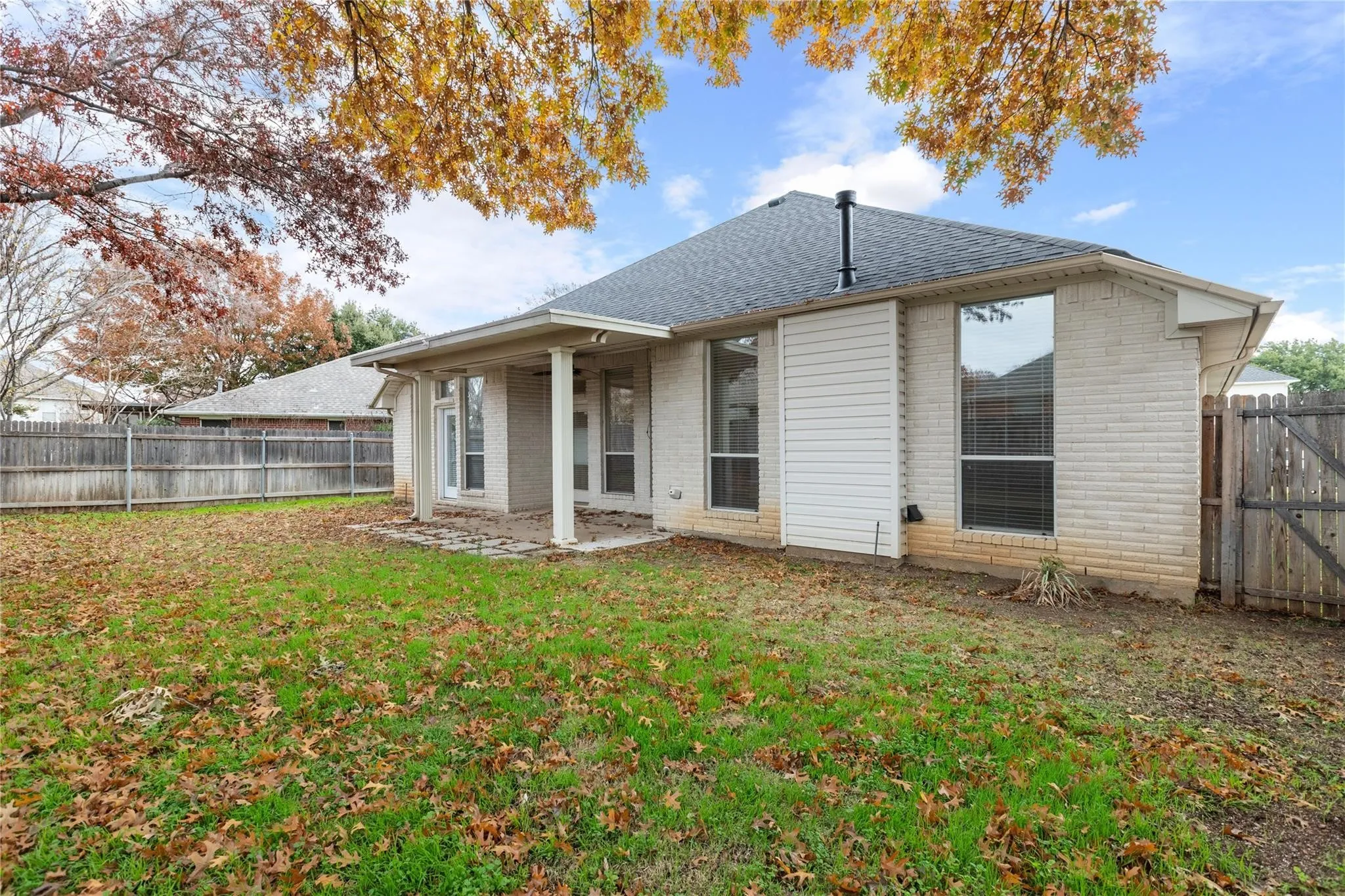 Expansive backyard featuring a covered patio, a wood privacy fence, and a gate