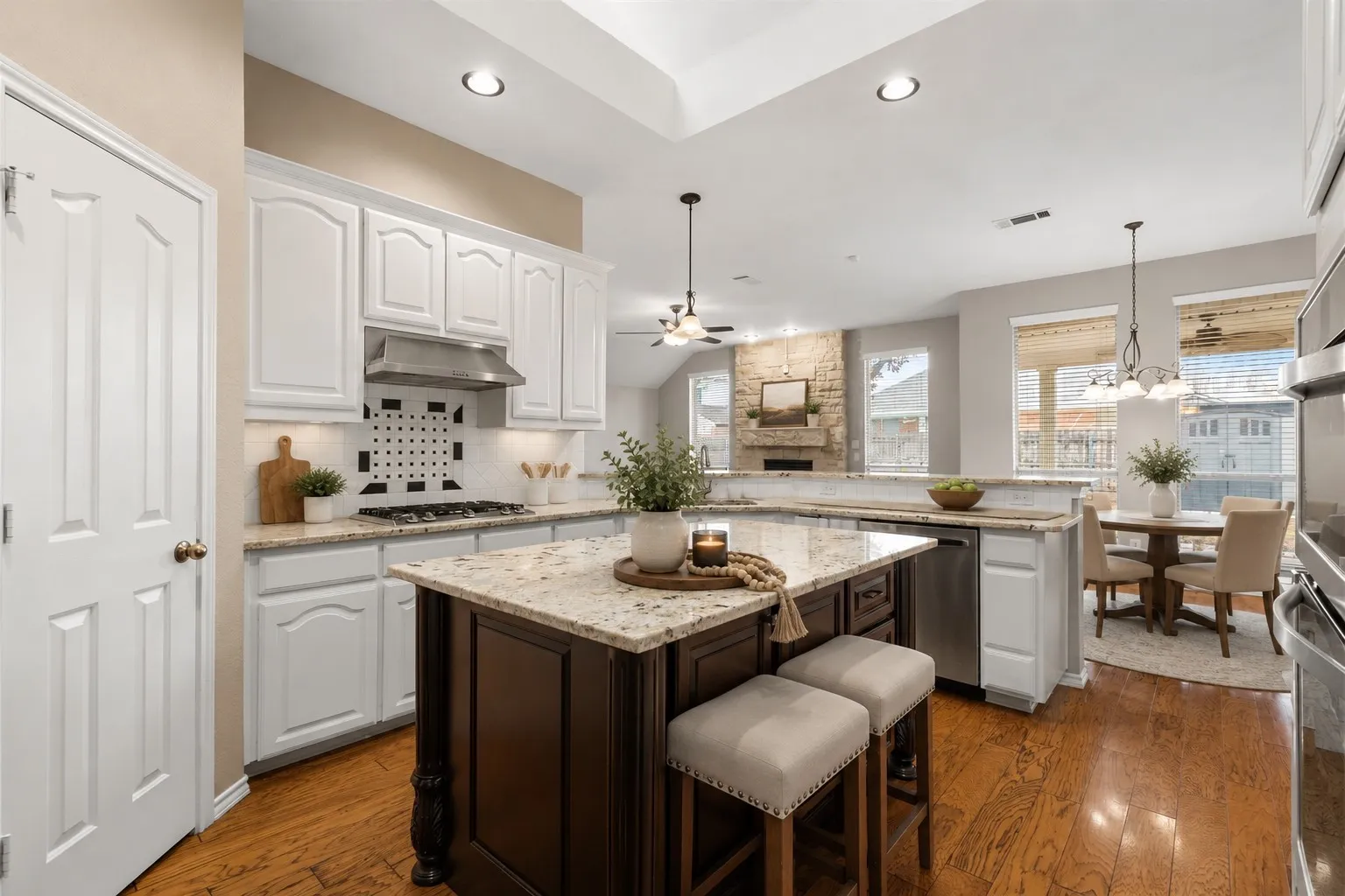 Kitchen featuring a central island with countertop seating, stainless steel appliances, wood-finish flooring, recessed lighting, and white cabinetry