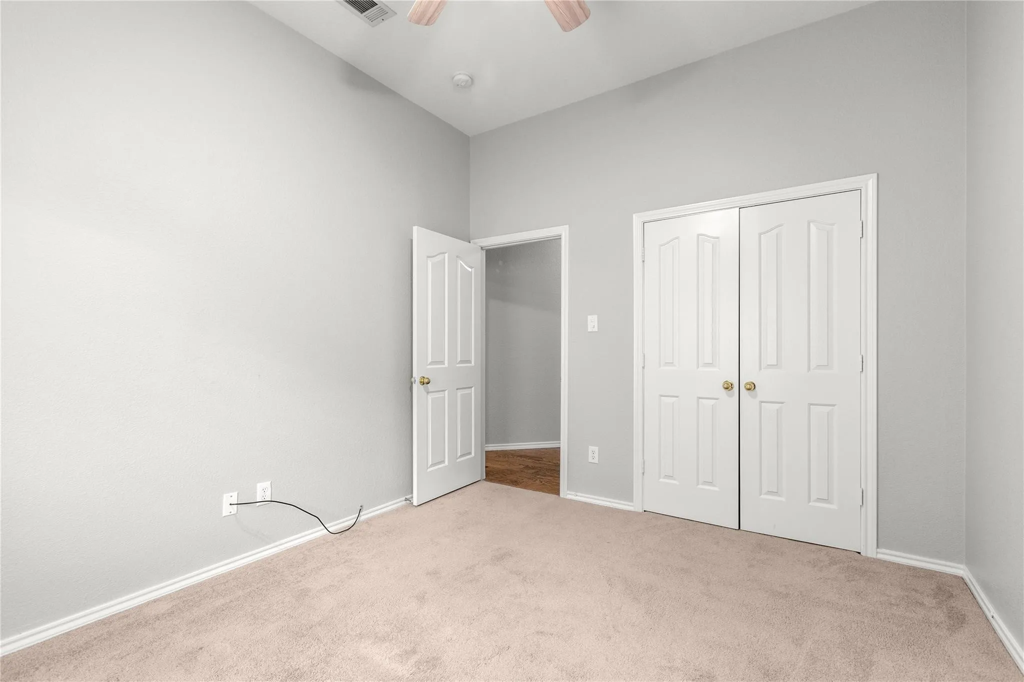 Carpeted flooring, vaulted ceiling, neutral wall tones, white bi-fold closet doors, and a white paneled door