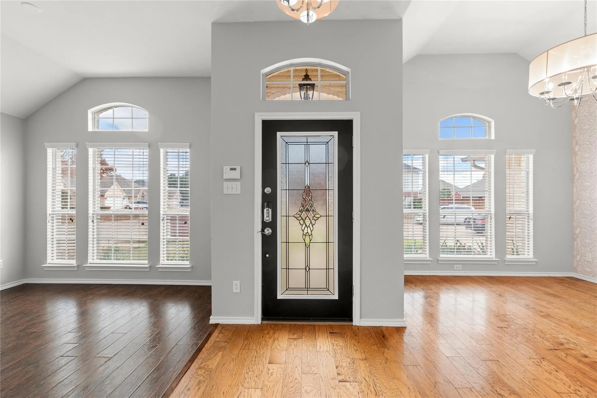 Two-story entryway featuring a leaded glass door, transom window, and vaulted ceilings