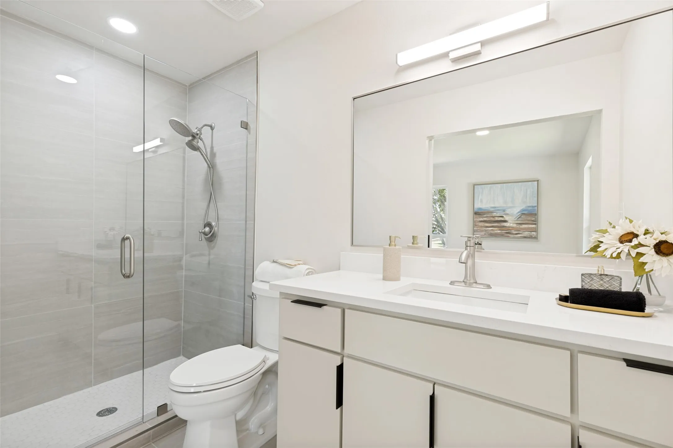 Glass-enclosed shower with tiled walls and rainfall showerhead