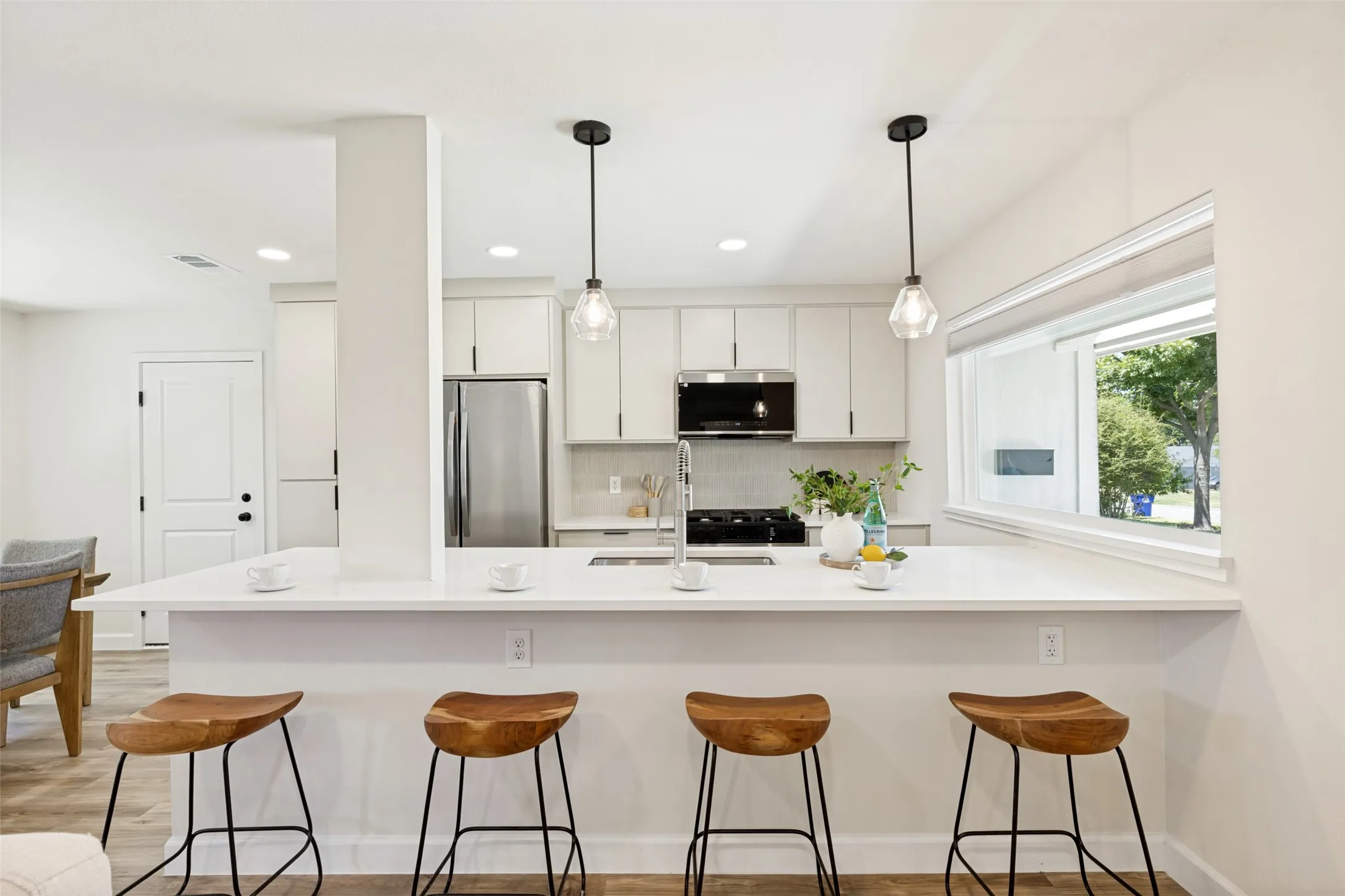 Modern kitchen featuring white cabinetry, stainless steel appliances, a white quartz countertop, and pendant lighting