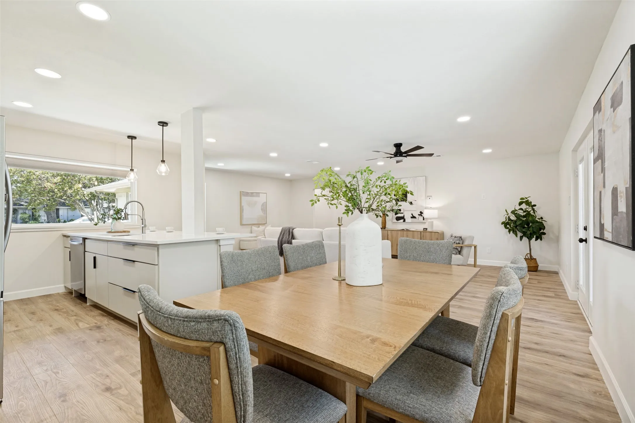 Open-concept living space featuring wood-finish flooring, recessed lighting, and a modern kitchen island with pendant lighting