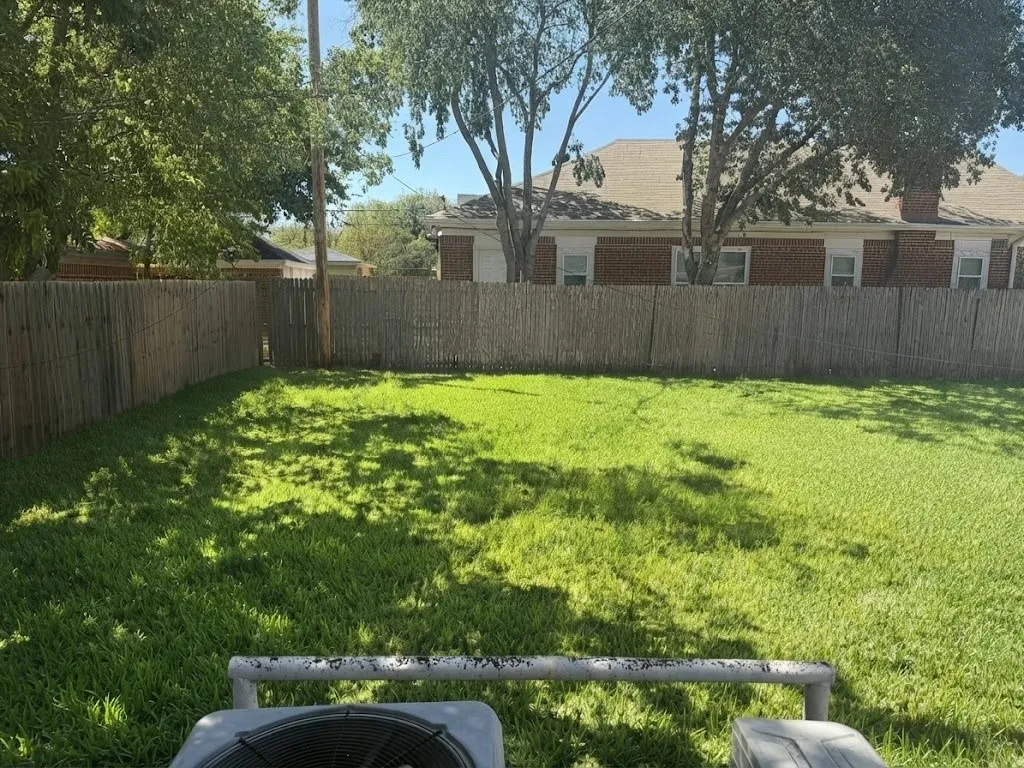 Expansive grassy yard area with partial shade and wood privacy fencing