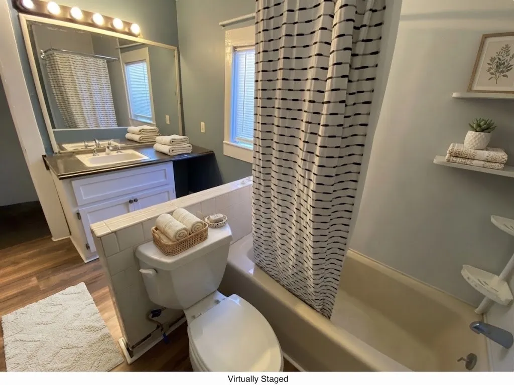 Bathroom featuring a single vanity, undermount sink, white cabinetry, and a bathtub with shower