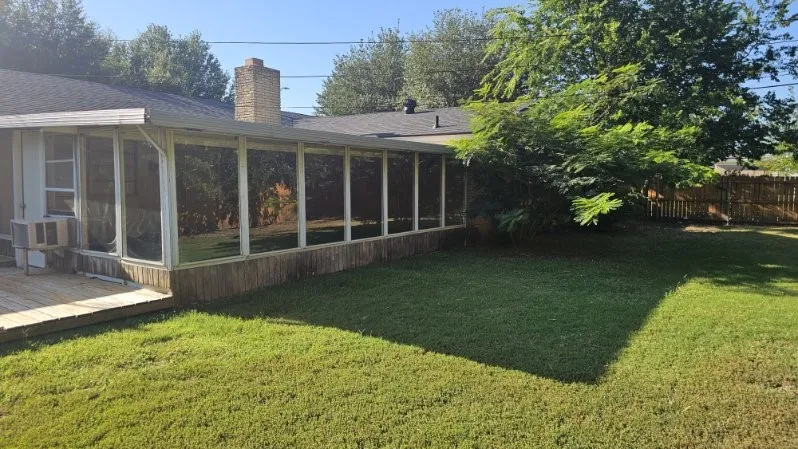 Screened porch with wood-finish siding, an attached wood deck, and a grass lawn