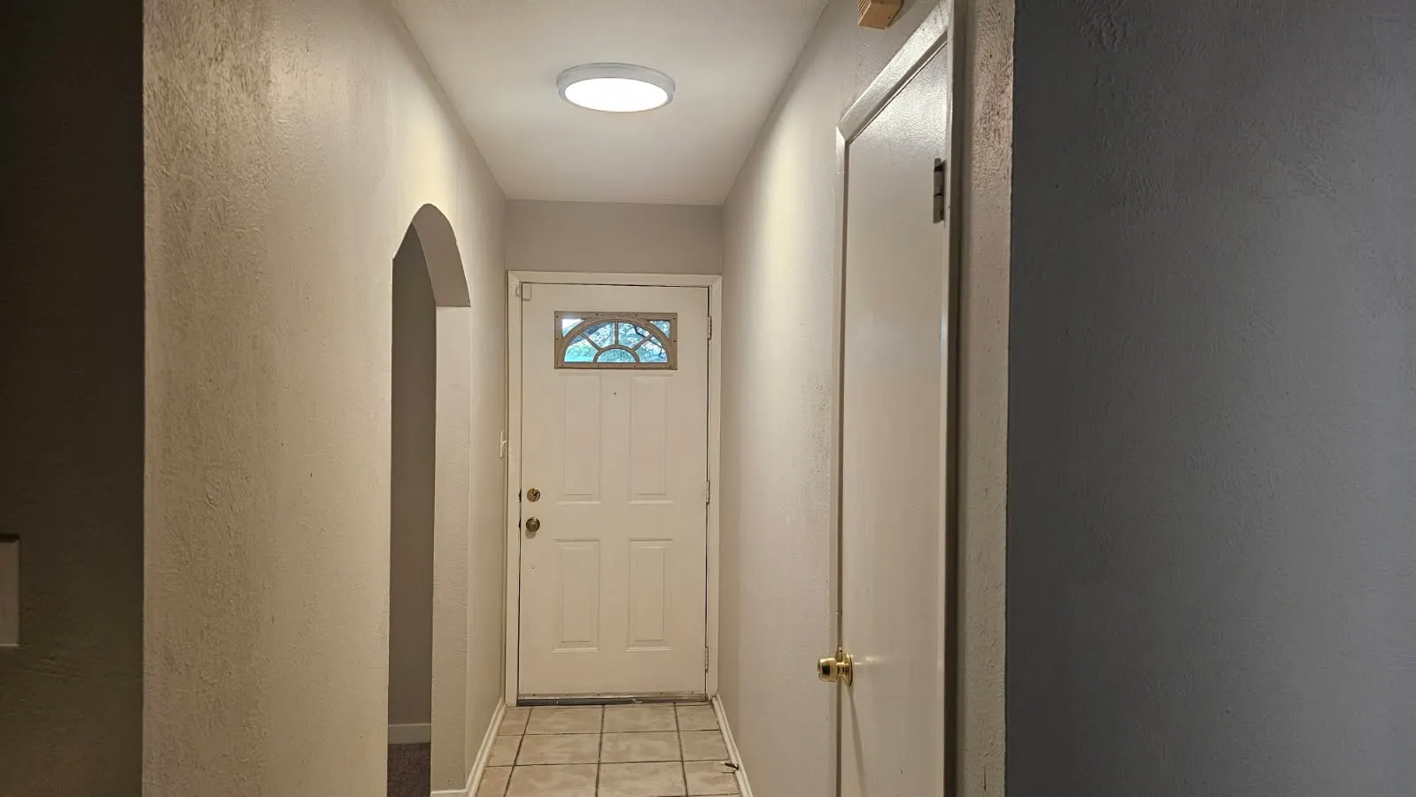 Entryway featuring tiled flooring, an arched doorway, and a white front door with decorative glass