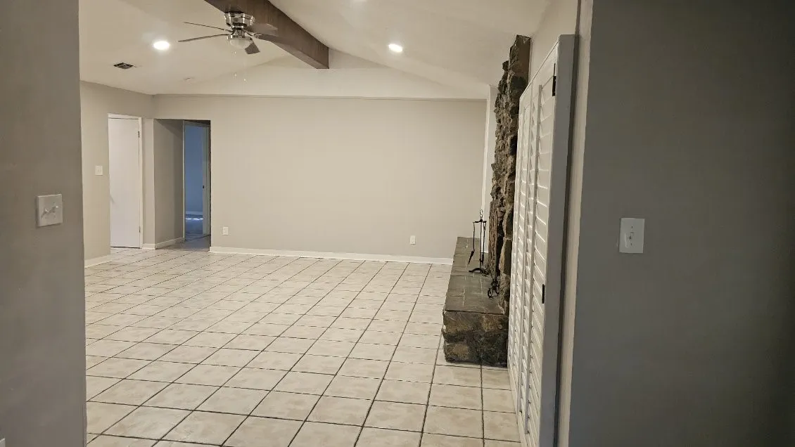 Spacious open floor plan with ceramic tile flooring throughout, recessed ceiling lighting, and exposed ceiling beams