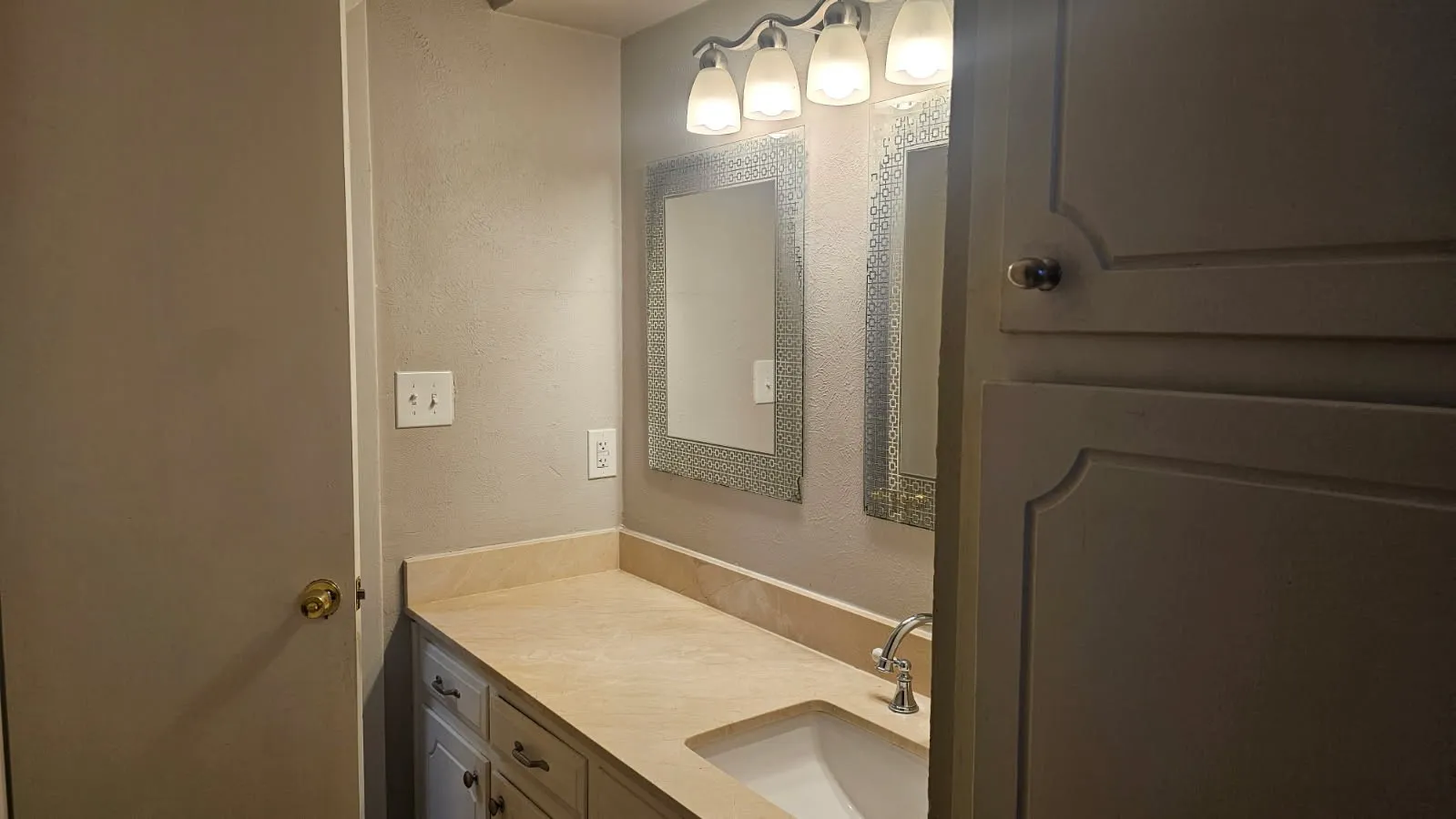 Double vanity with integrated sinks, light-toned countertop, and dual framed mirrors with overhead lighting