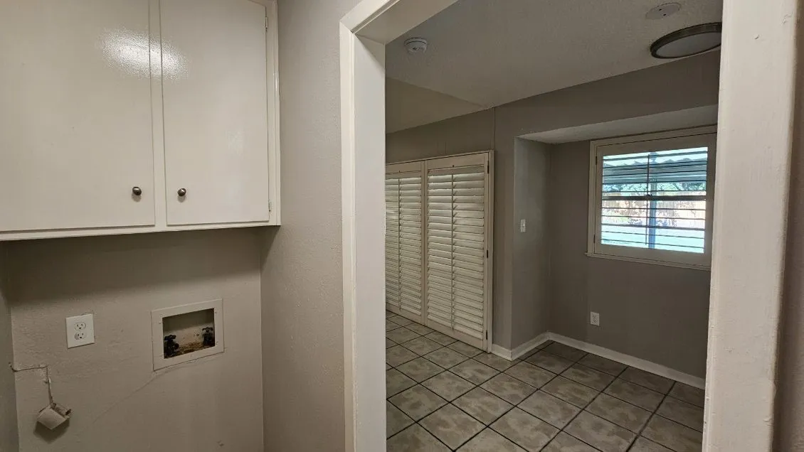 White cabinetry, tile flooring, window with plantation shutters, recessed lighting, and a surface-mount light fixture