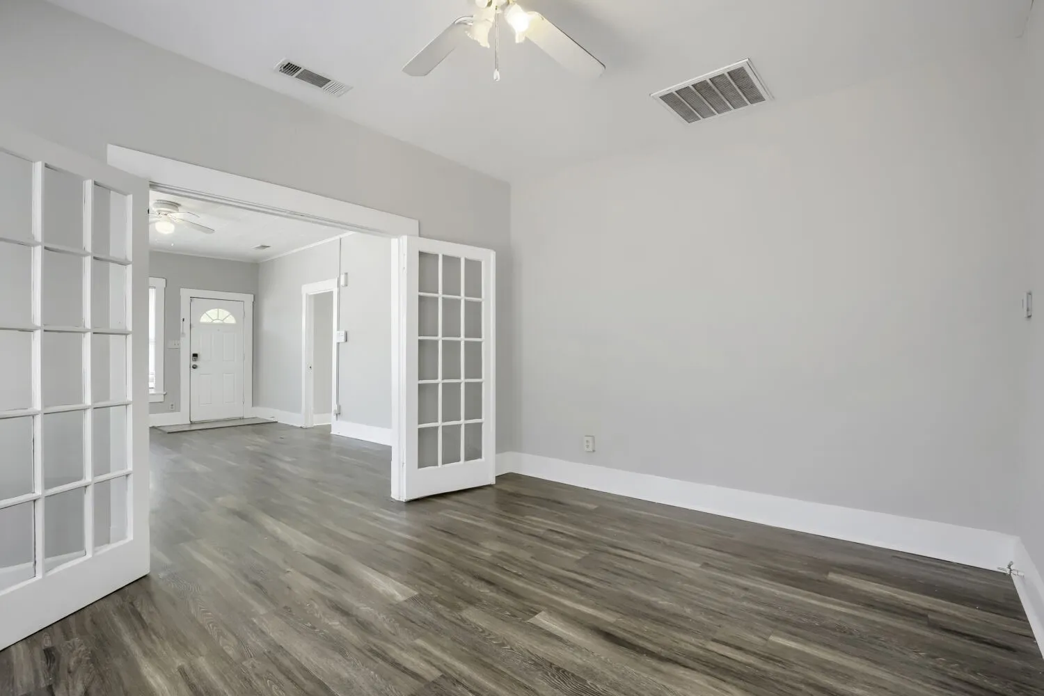 Bright, open interior featuring gleaming wood-finish flooring, crisp white trim and French doors with multiple glass panes, and recessed ceiling lighting throughout
