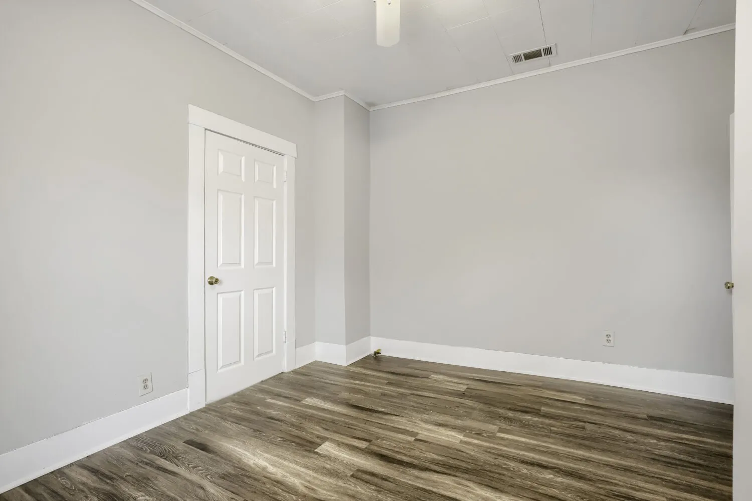 Bright, neutral bedroom featuring wood-finish flooring, fresh white walls, and clean architectural lines