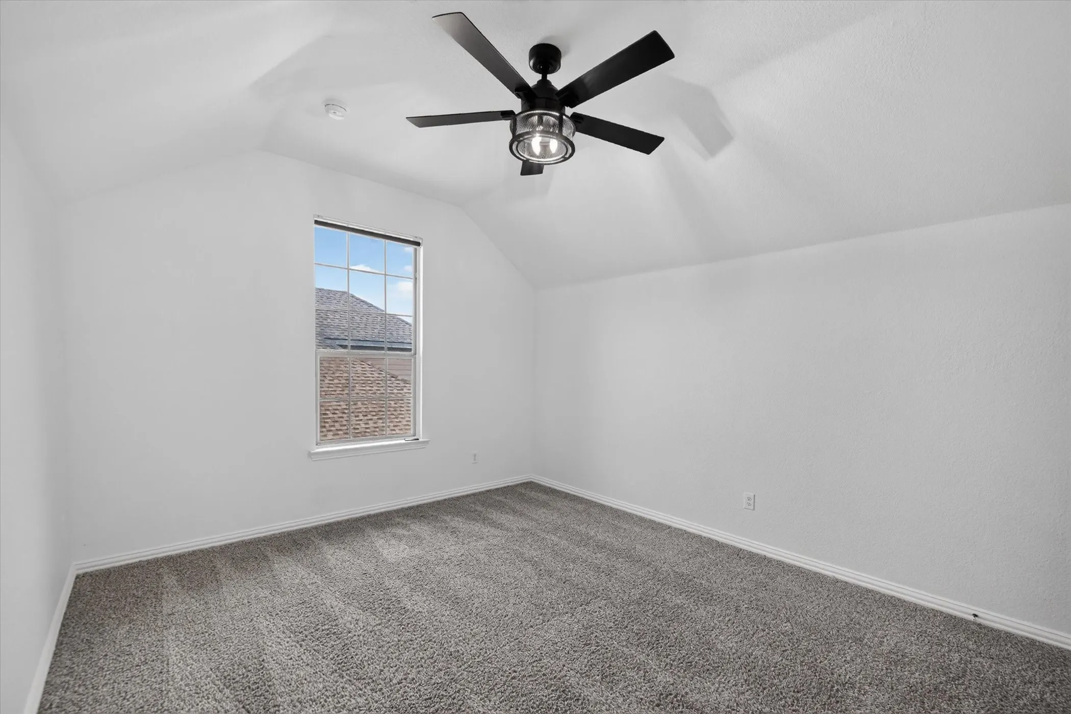 Angled ceiling, recessed window, dark-finish ceiling fan with integrated lighting, and neutral carpeting