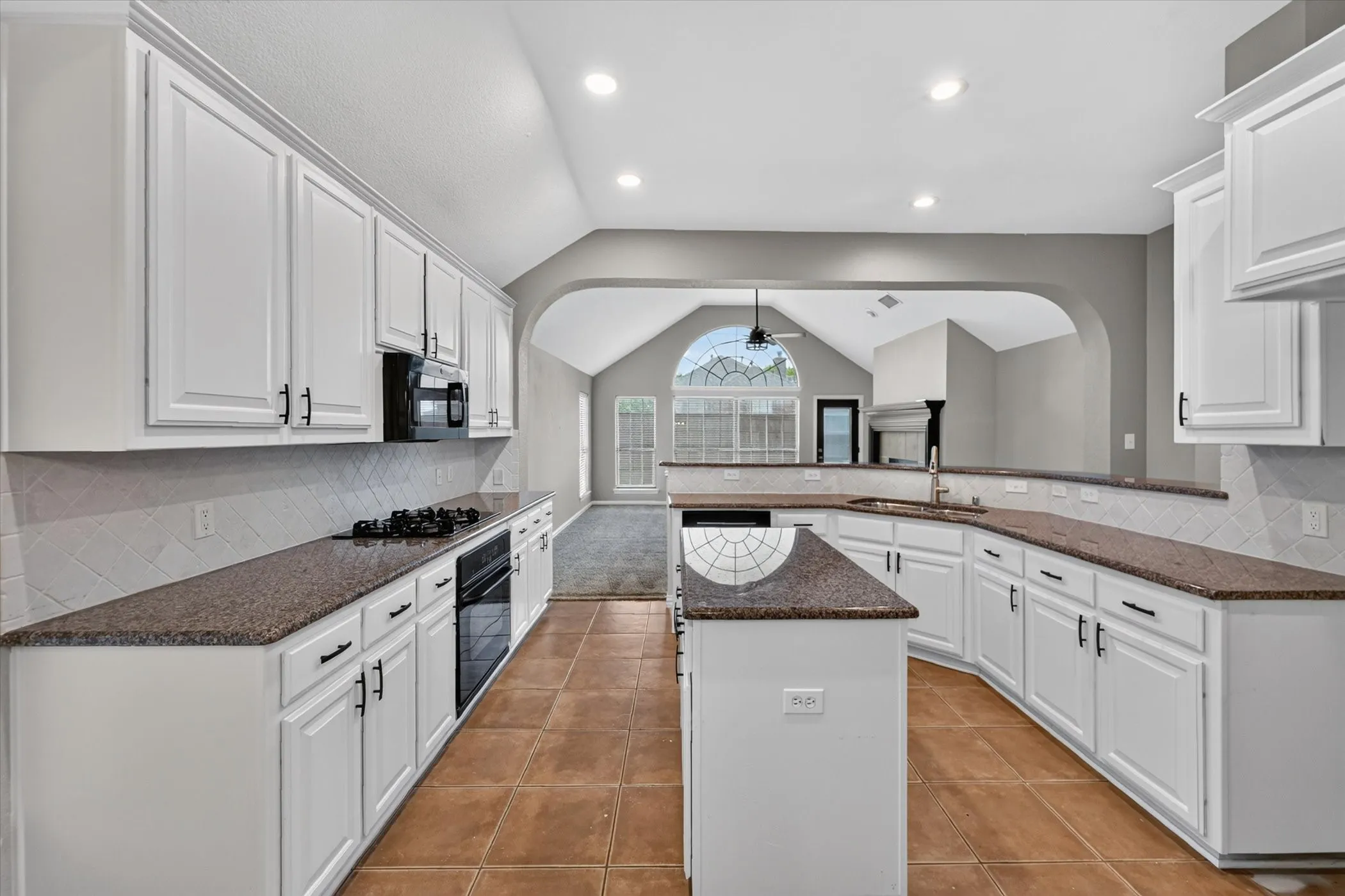 Kitchen with white cabinetry, dark countertops, tile flooring, and a central island