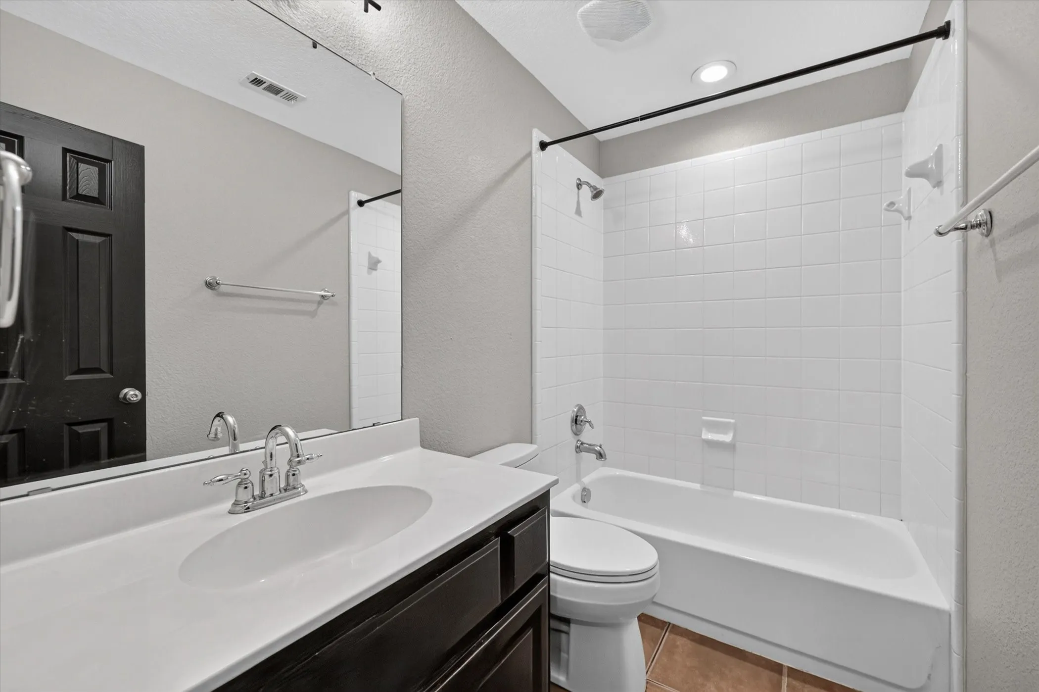 Bathroom featuring a white vanity with an undermount sink, chrome fixtures, a large wall-mounted mirror, and a shower-tub combination with white subway tile surround