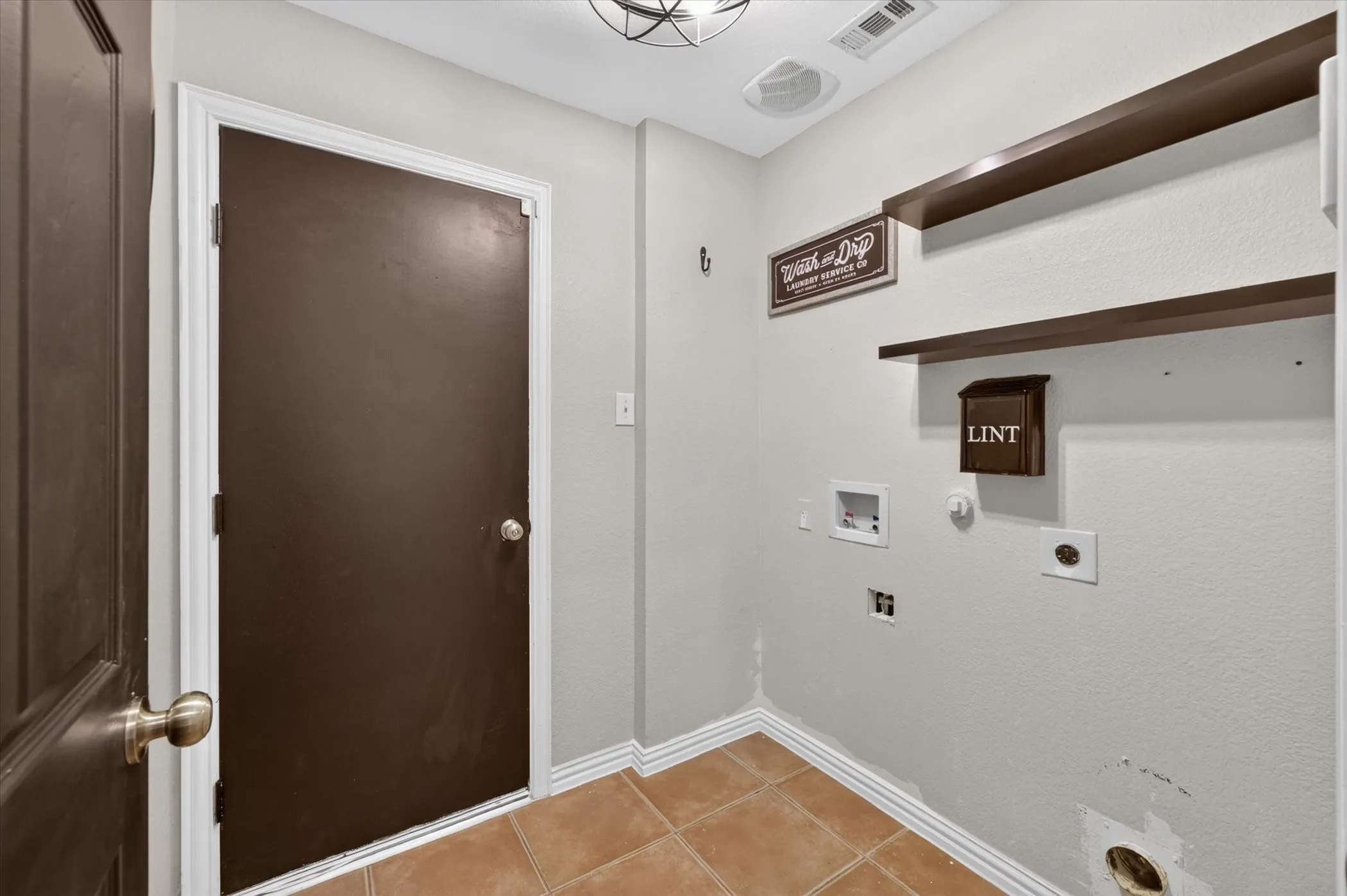 Laundry area with ceramic tile flooring and two wall-mounted wood shelves