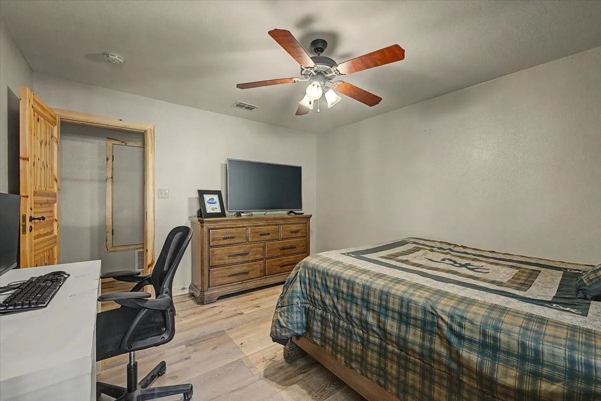 Wood-finish flooring throughout, ceiling fan with light fixture, and a solid wood door