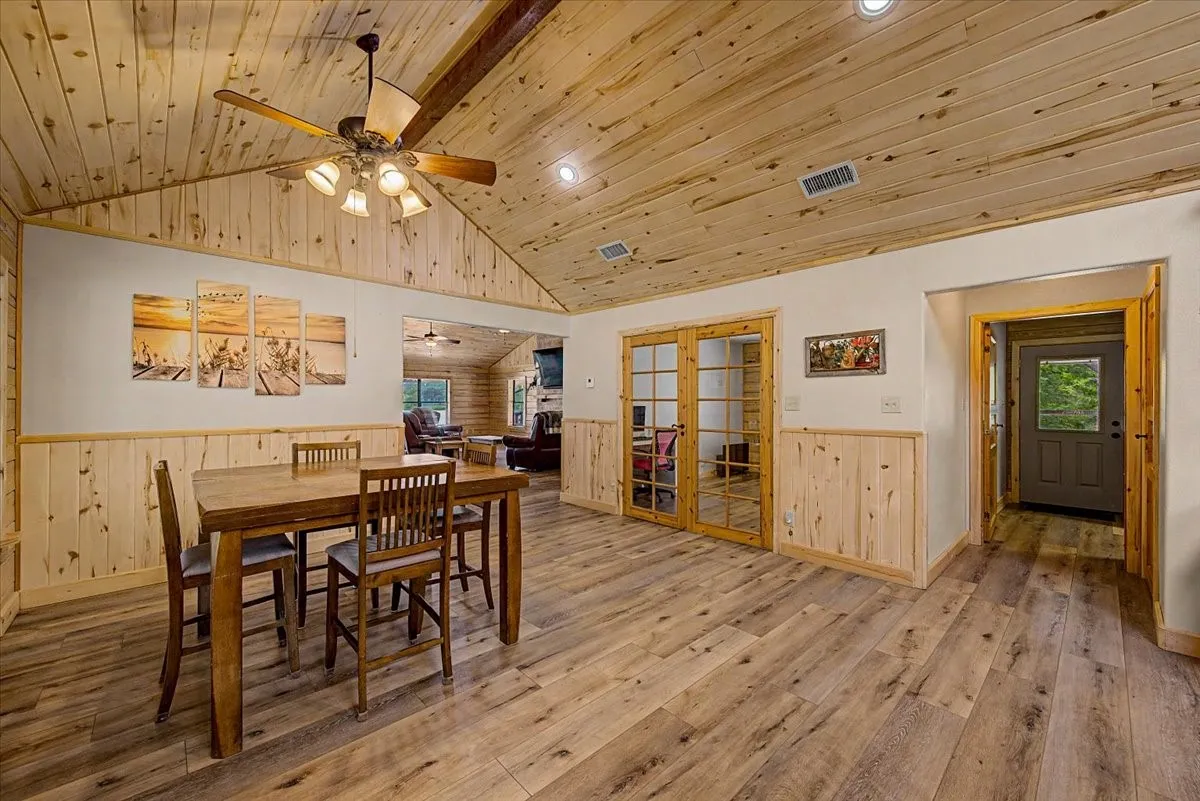 Vaulted wood-finish ceiling, wood-finish flooring, wood paneling, French doors, and recessed lighting