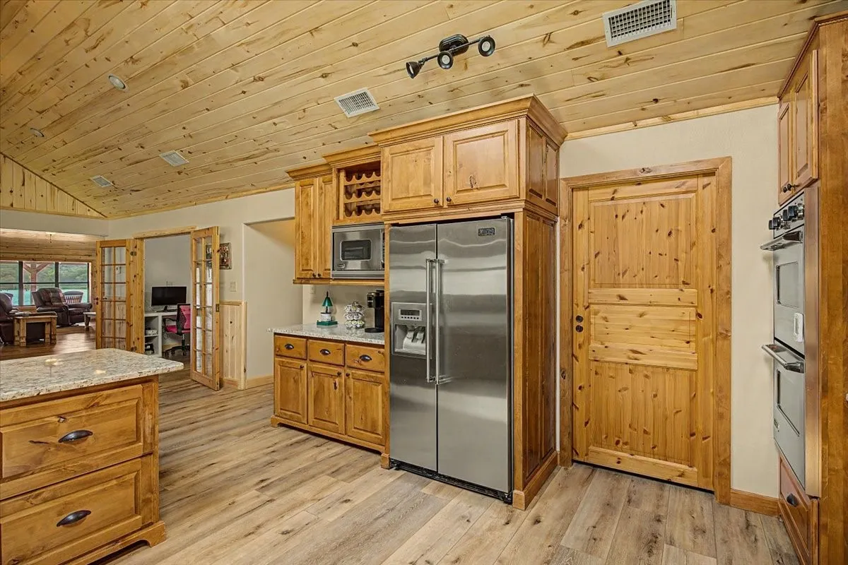 Kitchen with wood-finish flooring, wood cabinetry, granite countertops, and stainless steel appliances