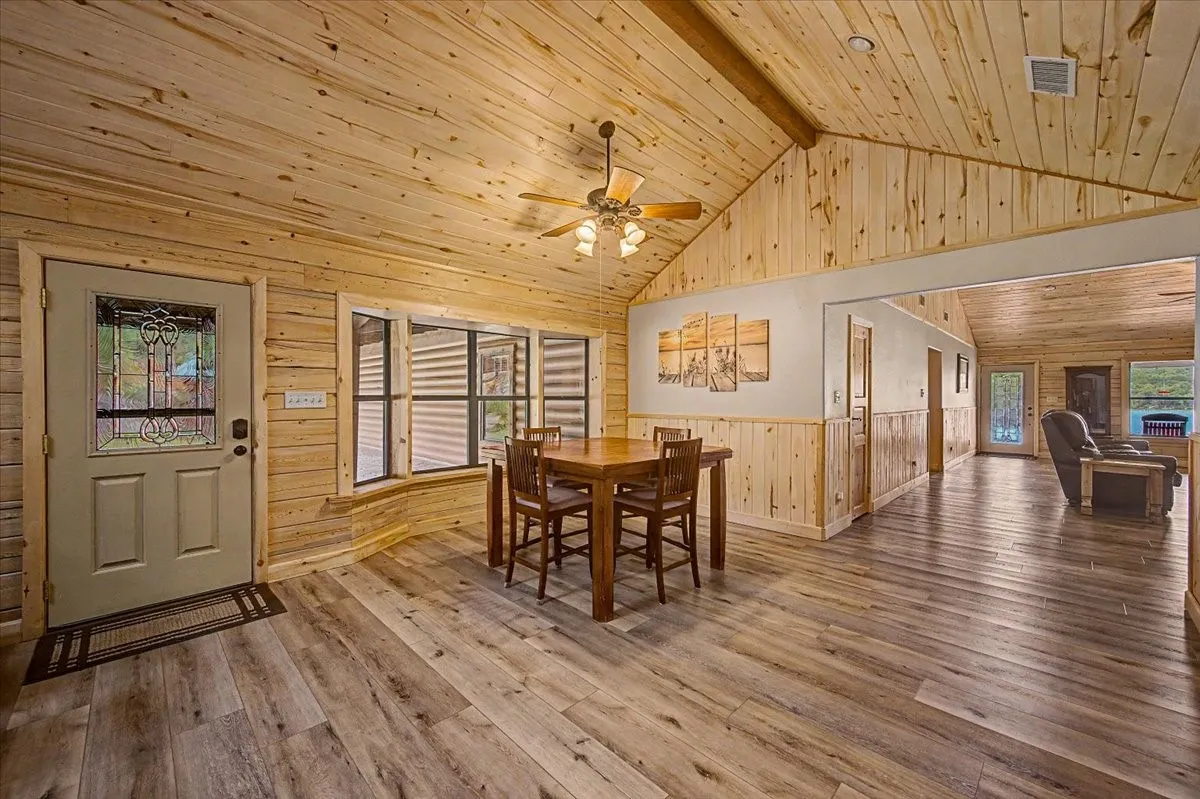 Vaulted wood-paneled ceiling, wood-finish flooring, wood-paneled walls, decorative glass entry door, and recessed wall paneling
