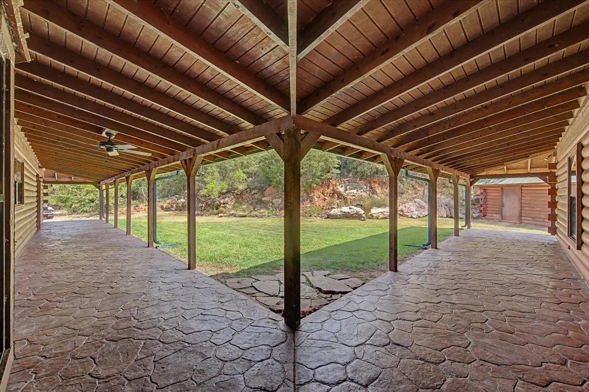 Covered patio with stamped concrete flooring, exposed wood beam ceiling, and a ceiling fan