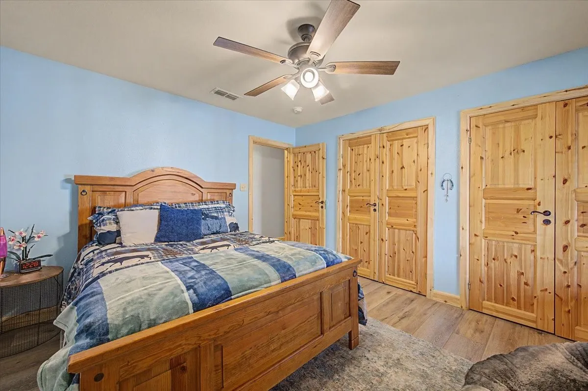 Wood-finish flooring with multiple paneled wood doors, ceiling fan, and recessed lighting