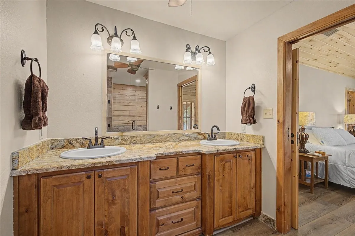 Double vanity with wood-finish cabinetry, light-toned countertop, and dual sinks