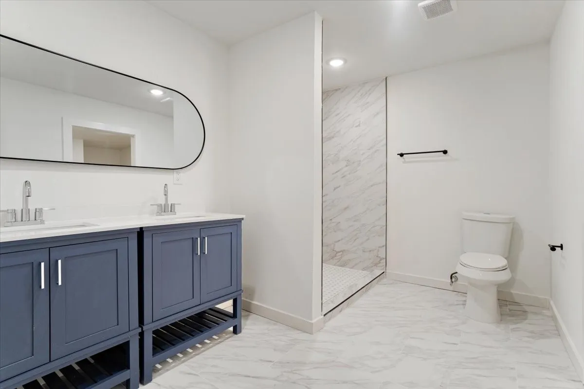 Dual vanity with blue cabinetry, white countertops, and chrome fixtures
