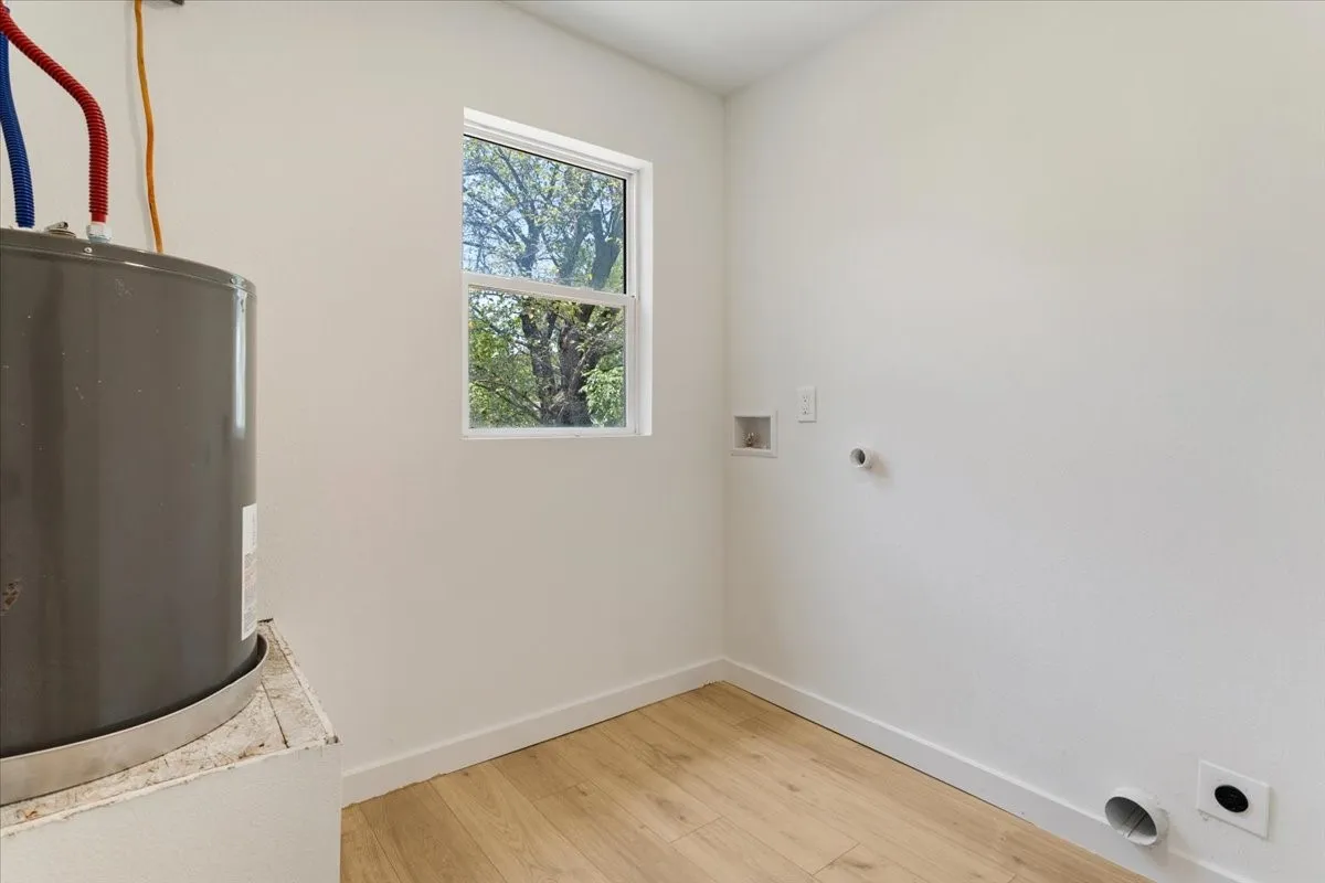 Utility room with wood-finish flooring, white walls, and a single window
