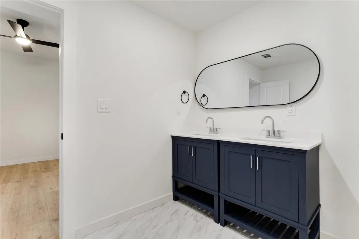 Dual navy blue vanity cabinets with white countertops, undermount sinks, and chrome fixtures