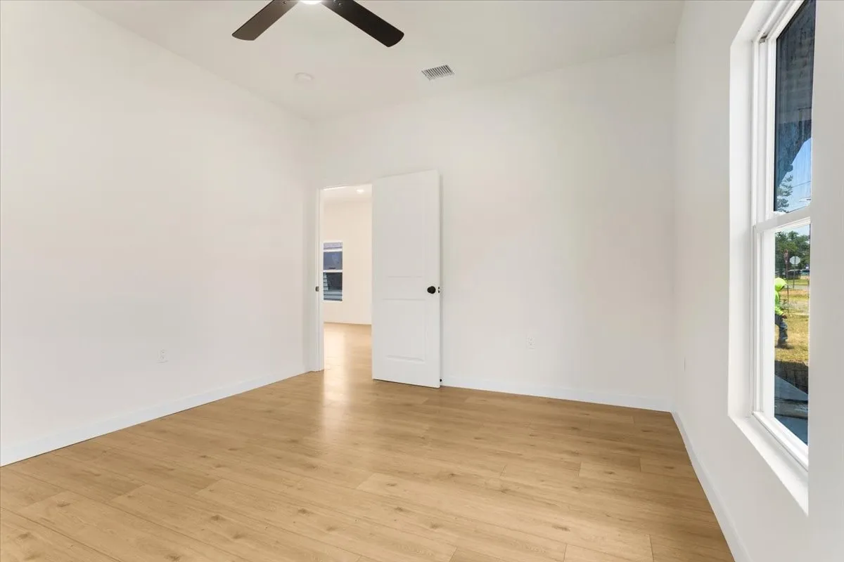 Bright room featuring wood-finish flooring, a ceiling fan, and a double-hung window