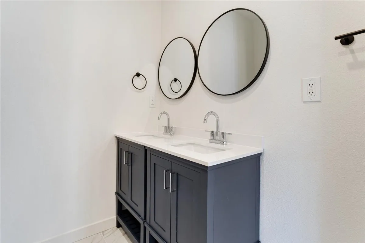 Dual vanity with dark wood-finish cabinetry, chrome fixtures, and white countertops